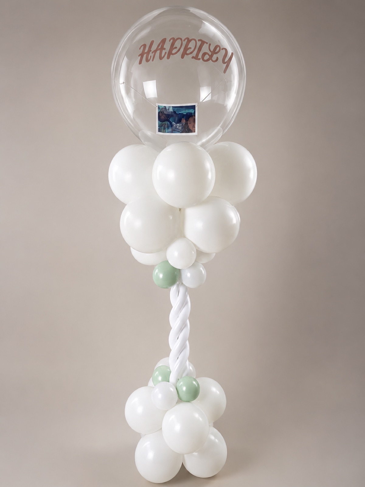 White and sage 'Happily' bubble balloon column for a wedding celebration