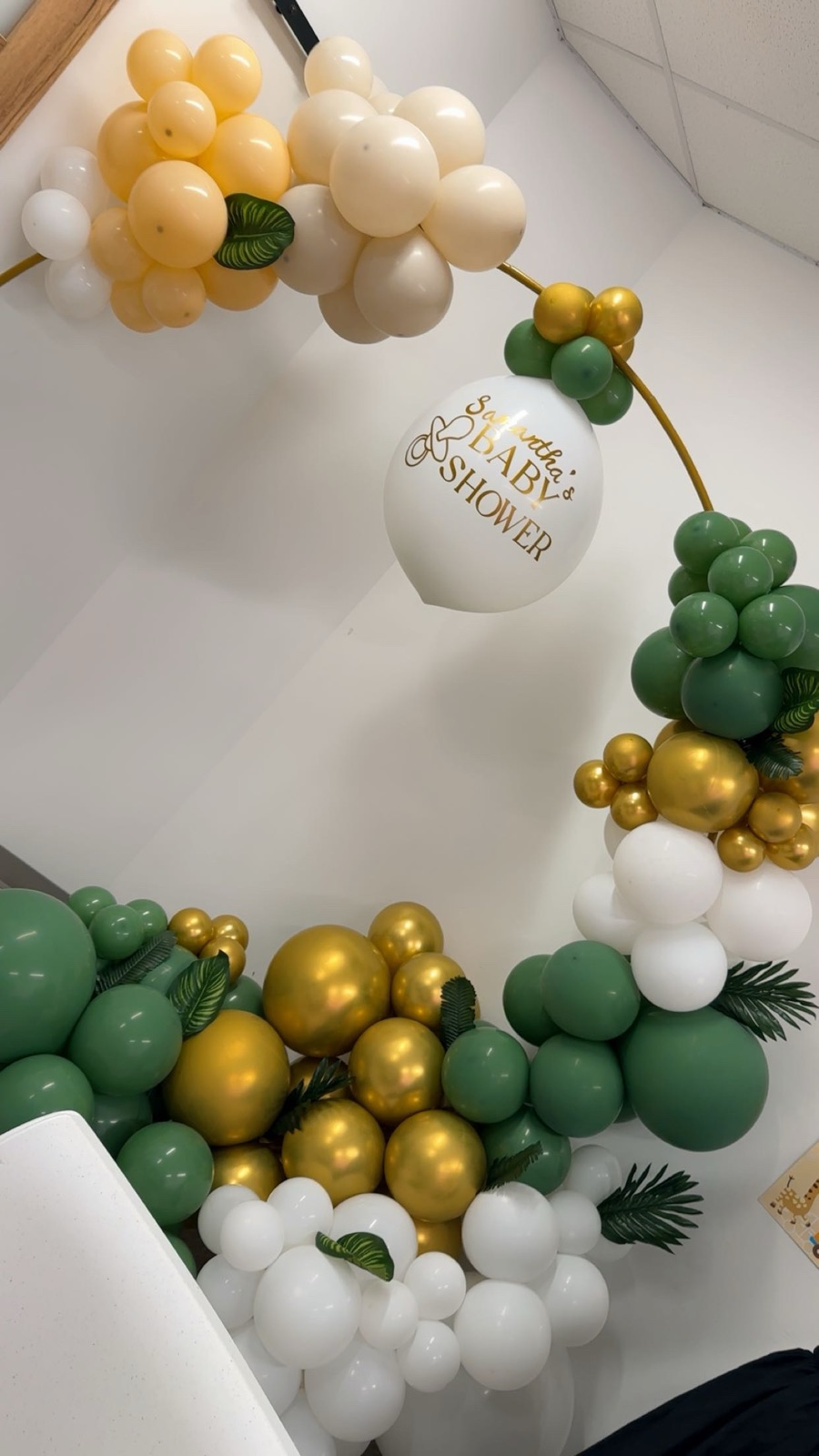 Green, gold, and white balloon hoop backdrop for a baby shower