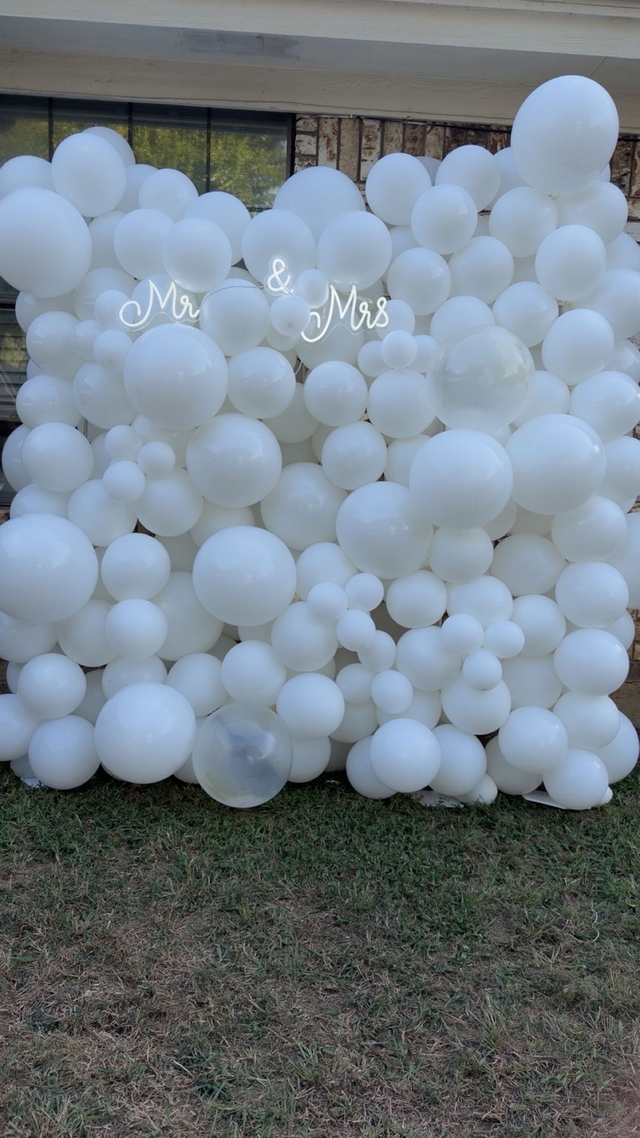 All-white balloon wall with a 'Mr & Mrs' neon sign for a wedding